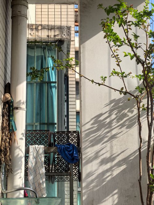Free Sunlit urban balcony with architectural details and a small tree. Stock Photo