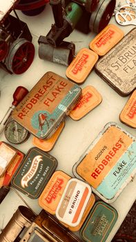 A collection of vintage tobacco tins displayed at a flea market with nostalgic decor.