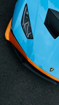 Close-up of a sleek luxury sports car in vibrant blue and orange colors, showcasing modern design and style.