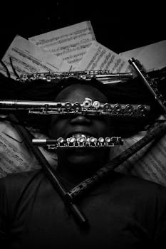 Artistic black and white photo of a flutist with flutes and sheet music.