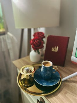 A stylish coffee setup with roses and a notebook on a wooden table, indoors.