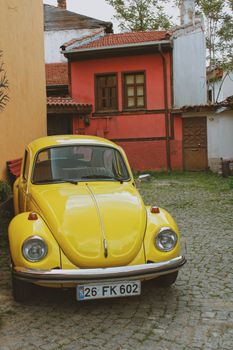 Classic yellow Volkswagen Beetle parked on cobblestone street in Eskişehir, Türkiye.