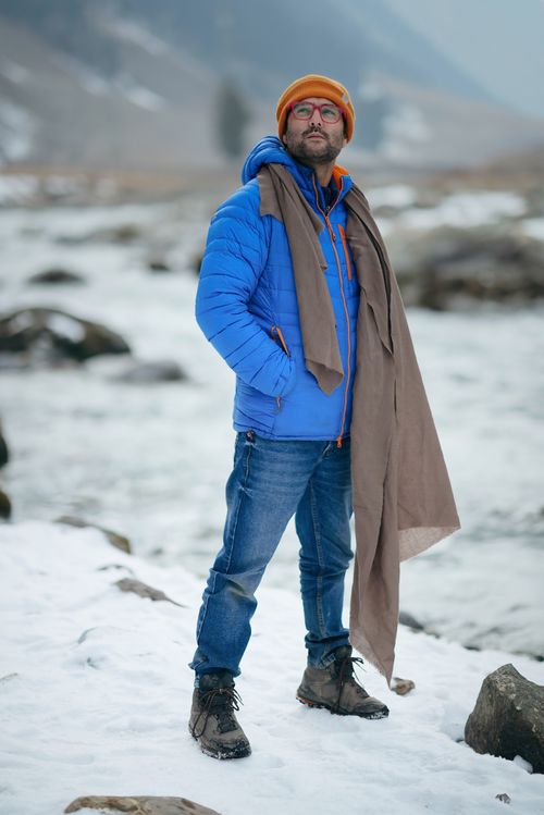 Free A hiker in winter clothing stands by a snowy river in the picturesque region of Jammu and Kashmir. Stock Photo