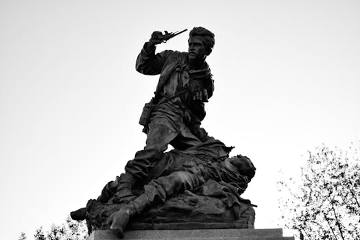 Scultura monumentale raffigurante una drammatica scena di guerra con due soldati in bianco e nero, che cattura l'intensità storica.