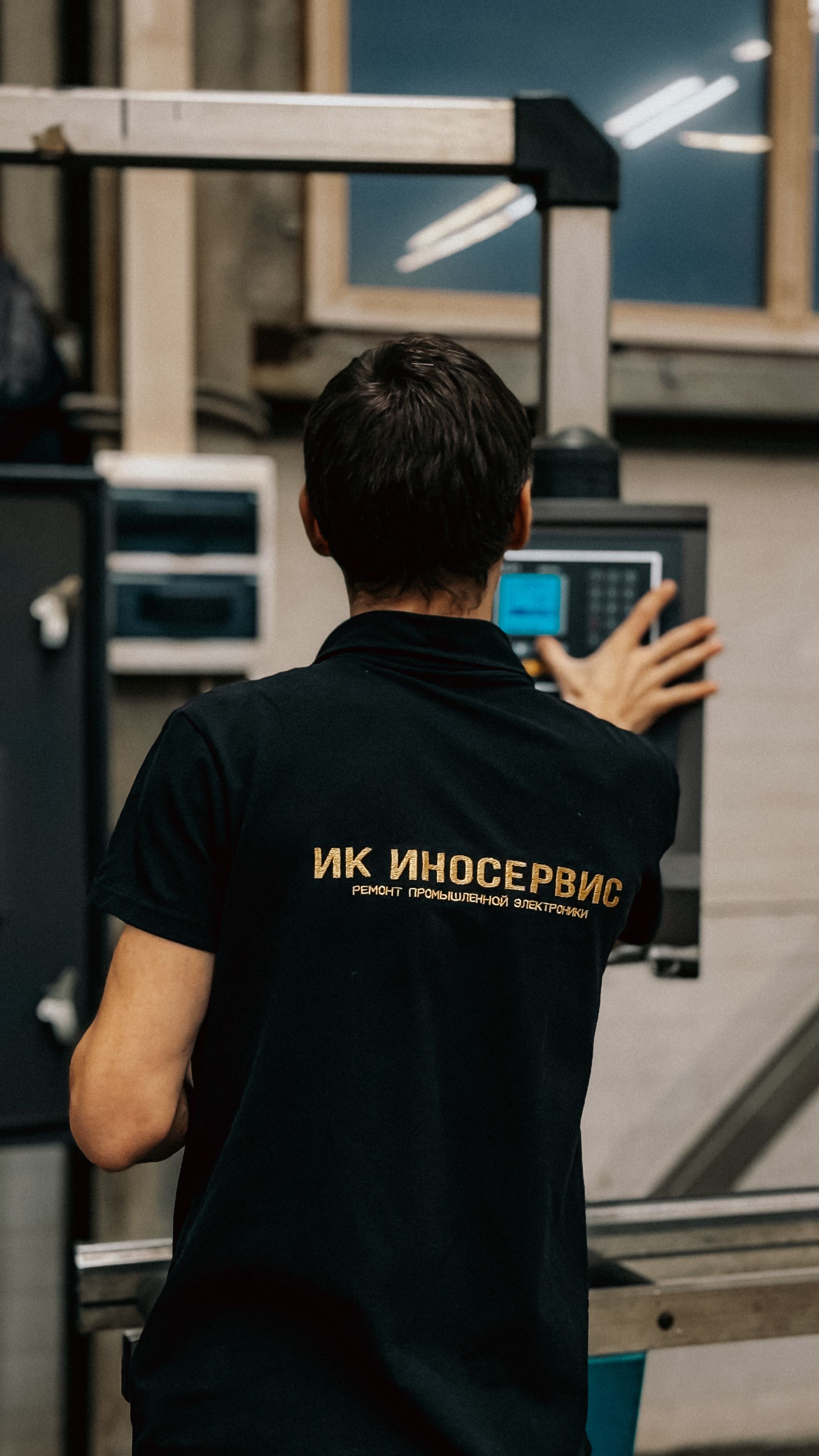 Back view of a technician operating a machine in an industrial setting.