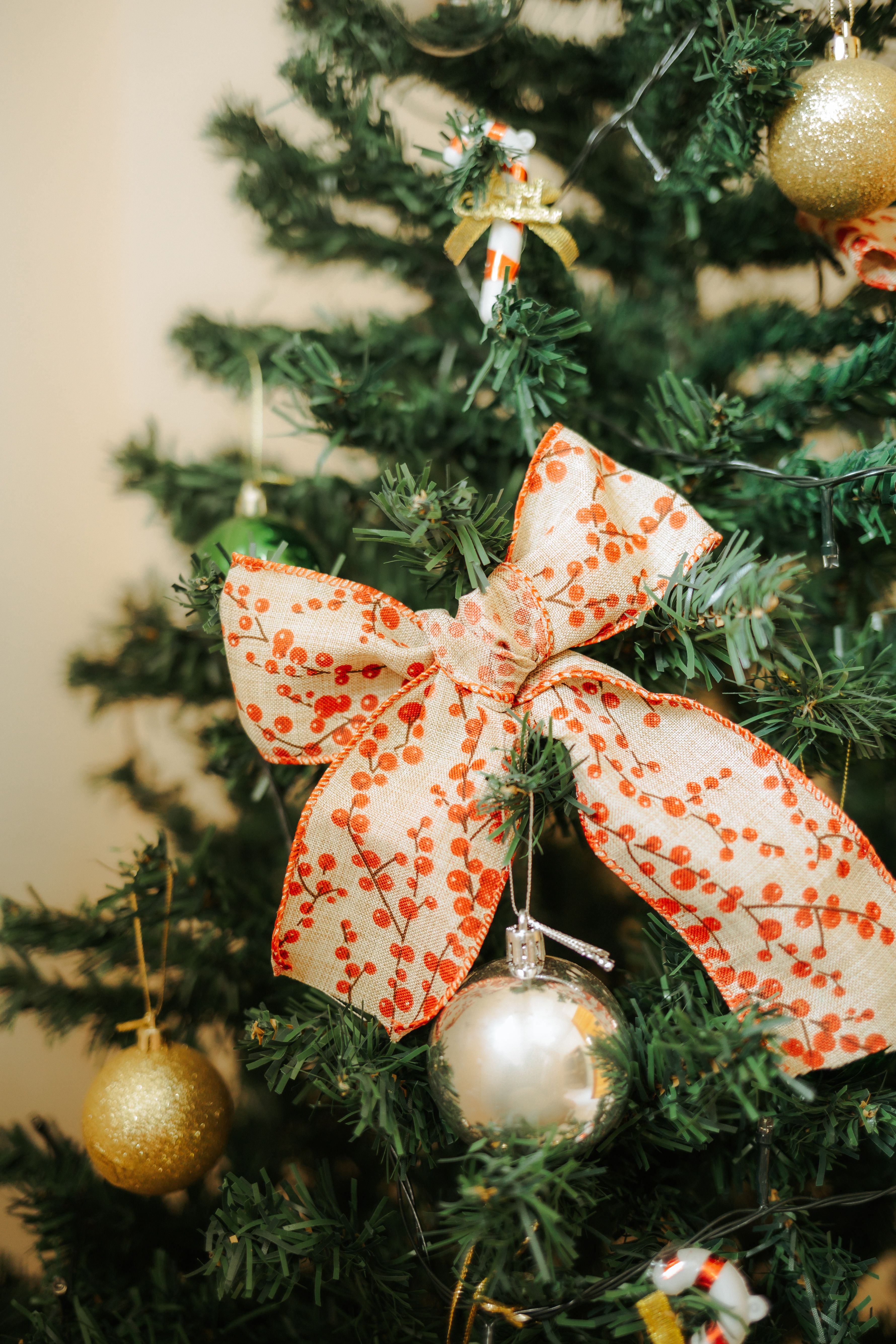 Gratis Albero di Natale festoso con decorazioni eleganti e un grande nastro rosso, che trasmette lo spirito delle feste. Foto a disposizione