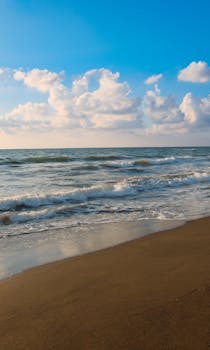 Tranquil beach with waves in İskenderun, Türkiye, under a bright blue sky.
