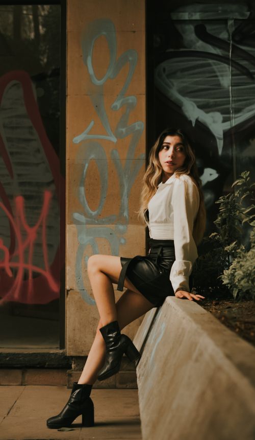 Free Stylish woman poses in urban setting with vibrant graffiti and moody lighting. Stock Photo