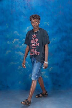 Smiling young man in casual attire with a humorous t-shirt, walking confidently.