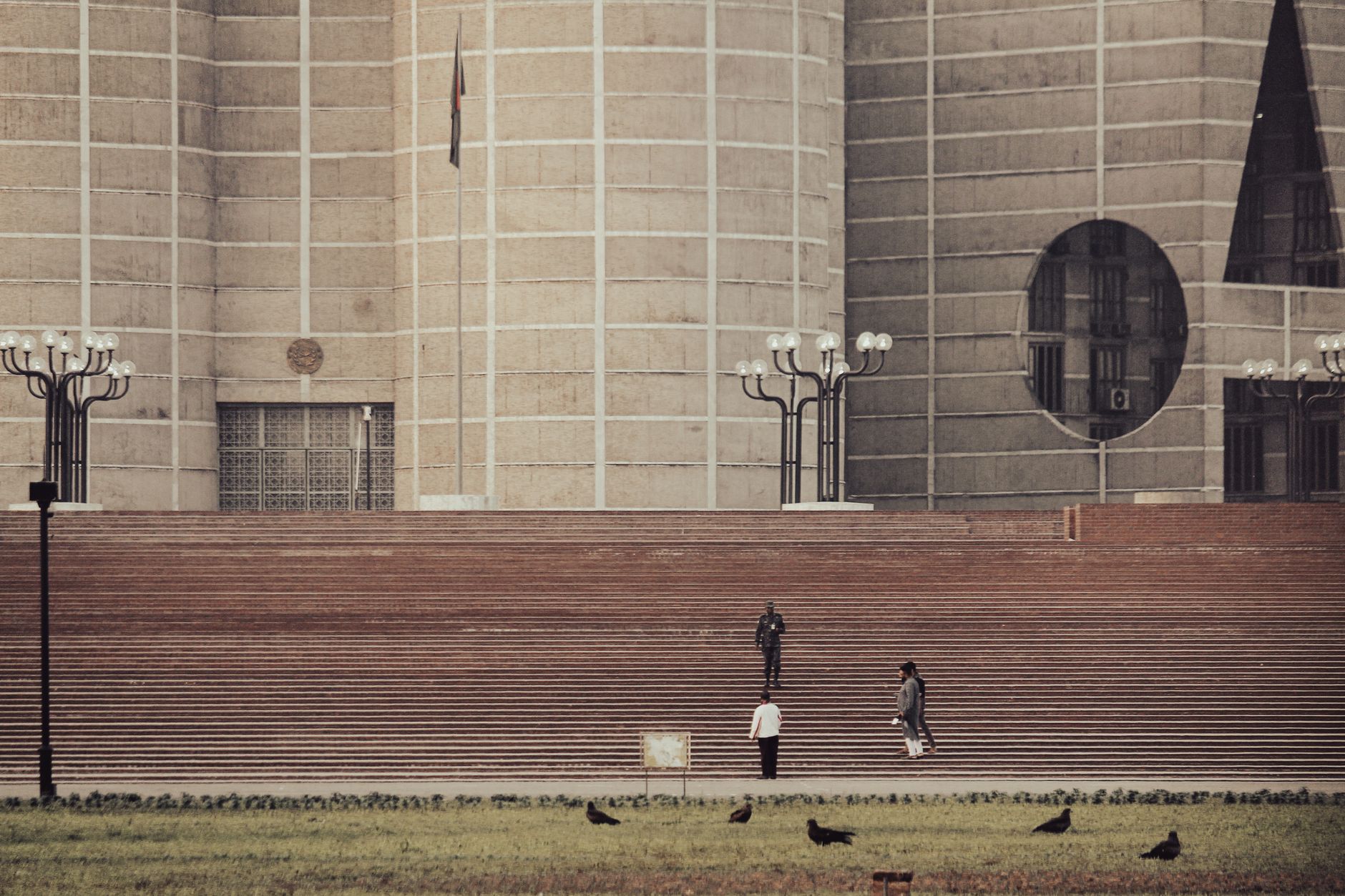View of the iconic Jatiyo Sangsad Bhaban in Dhaka with people and lawn.
