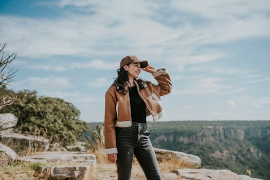 Young woman in casual attire enjoying a scenic mountain view on a sunny day.