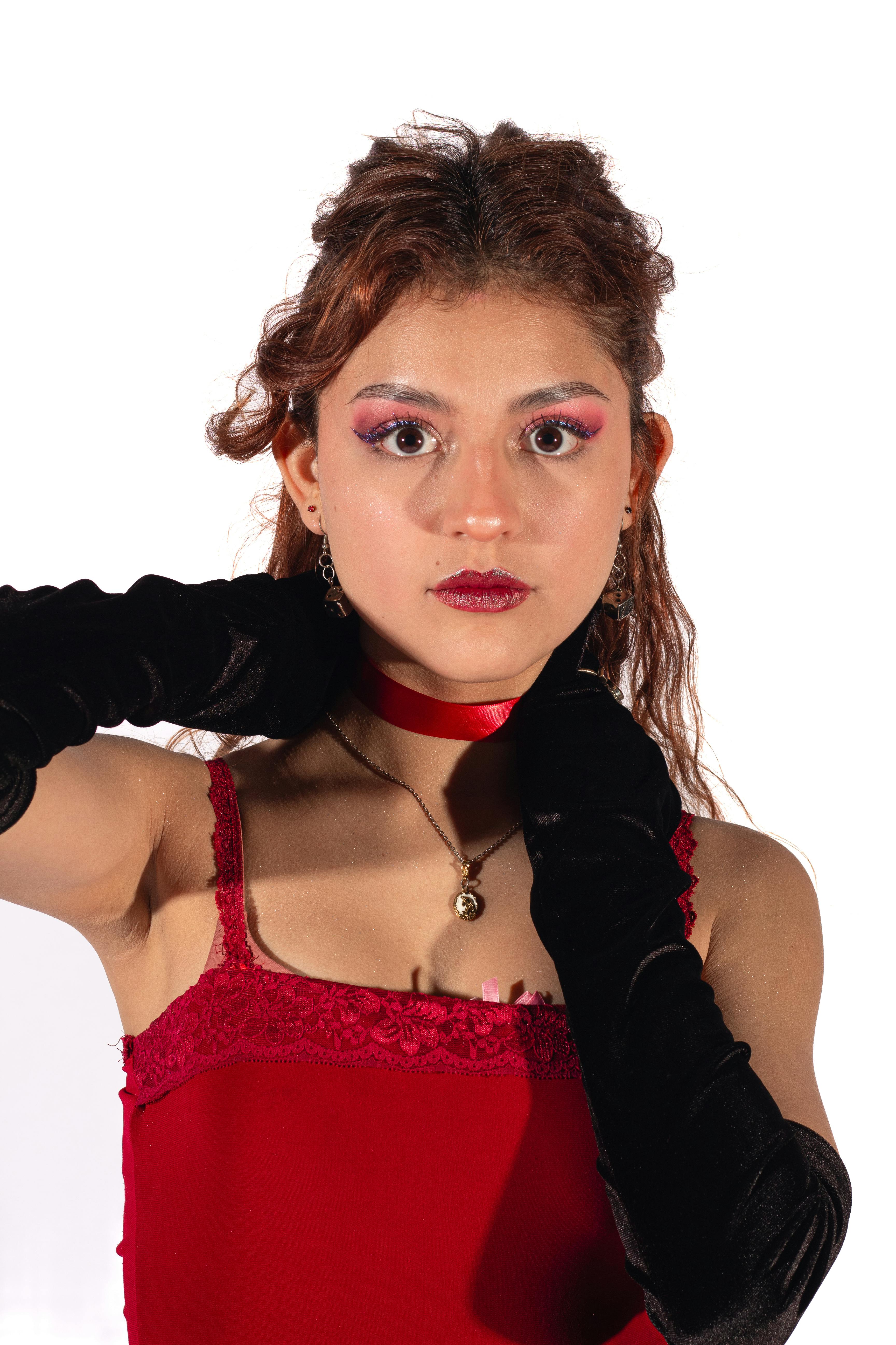 Безкоштовне Портрет молодої жінки в червоній сукні та рукавичках, що випромінює елегантність та стиль. стокове фото