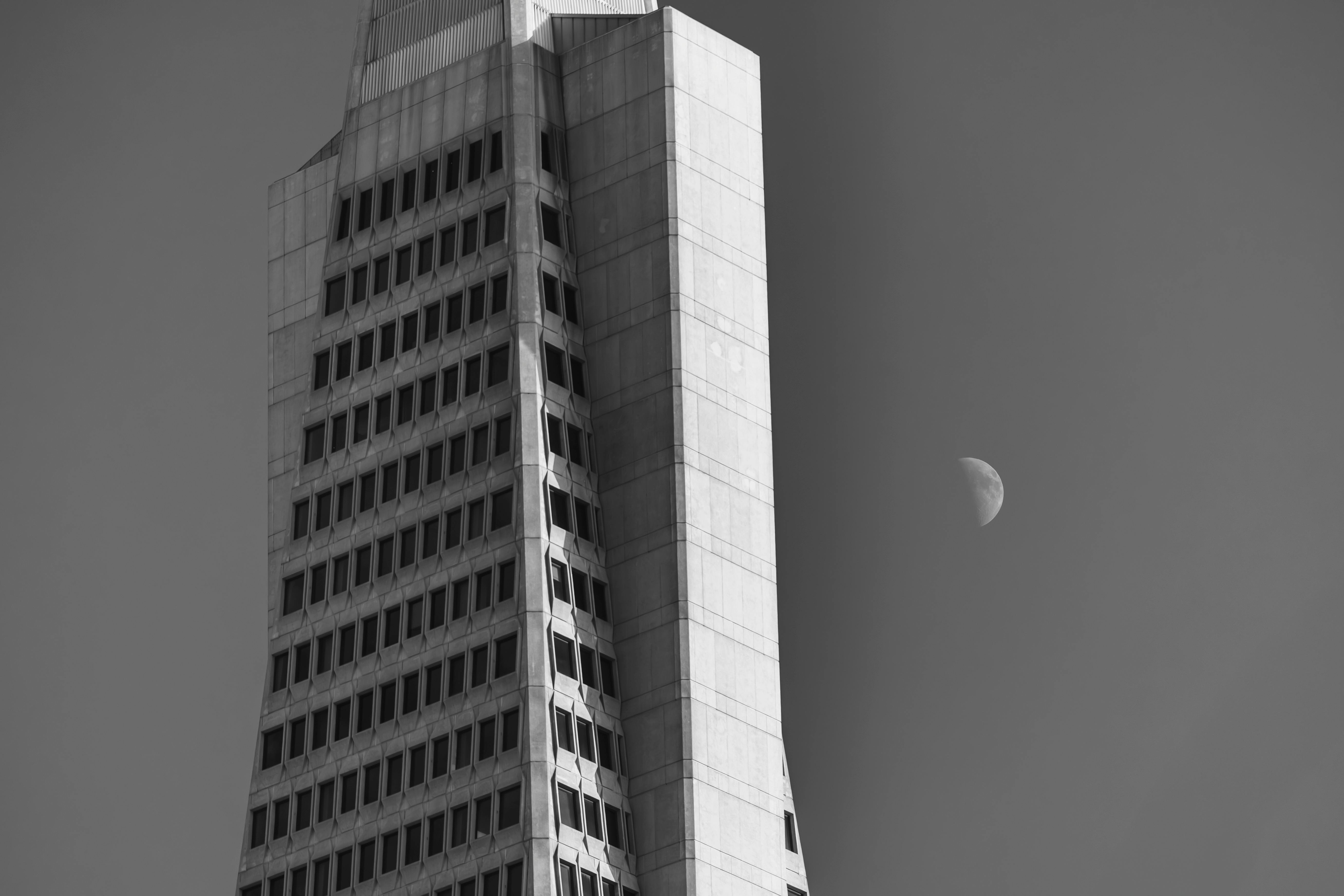 Ücretsiz Arkaplanında ay bulunan bir gökdelenin siyah beyaz mimari fotoğrafı. Stok Fotoğraflar