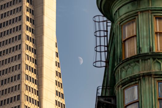 A striking view of urban architecture juxtaposed with the moon in daylight.