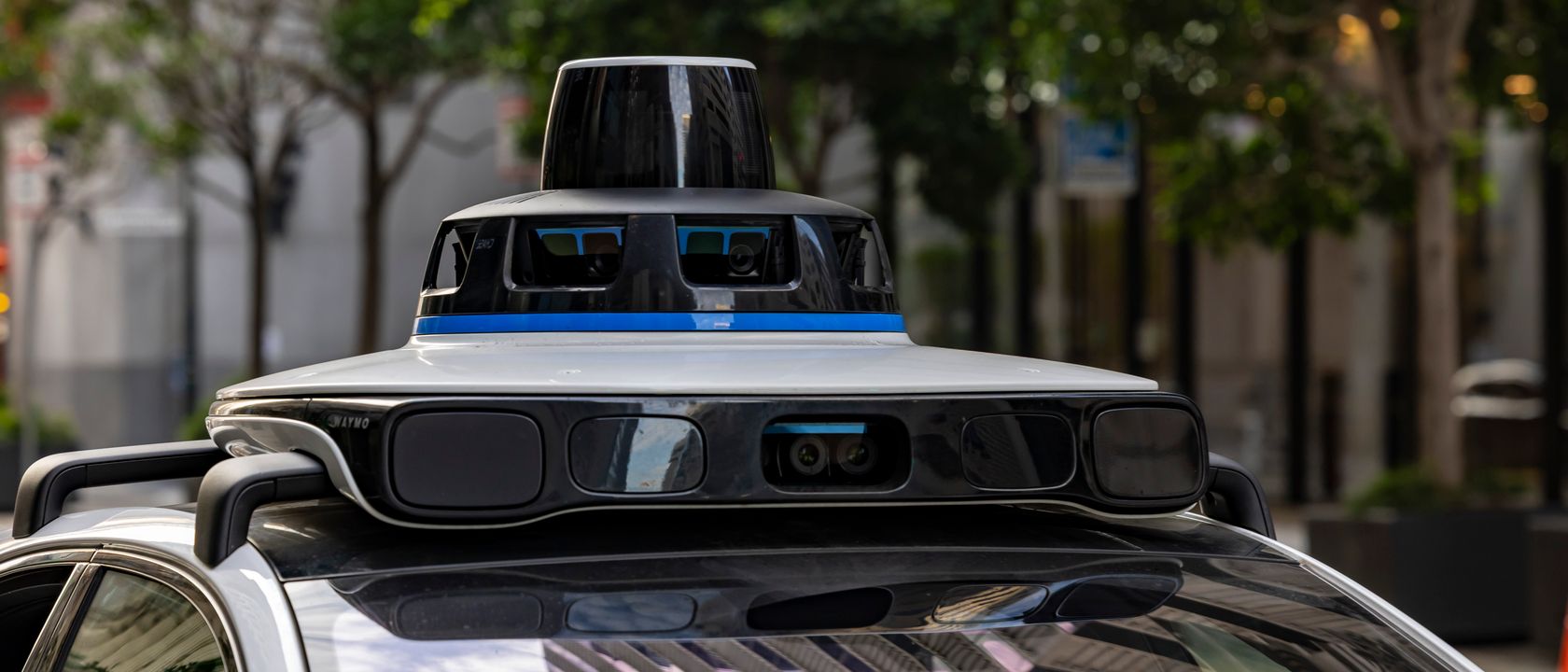 Detailed view of sensors atop an autonomous car, showcasing advanced technology in an urban setting.