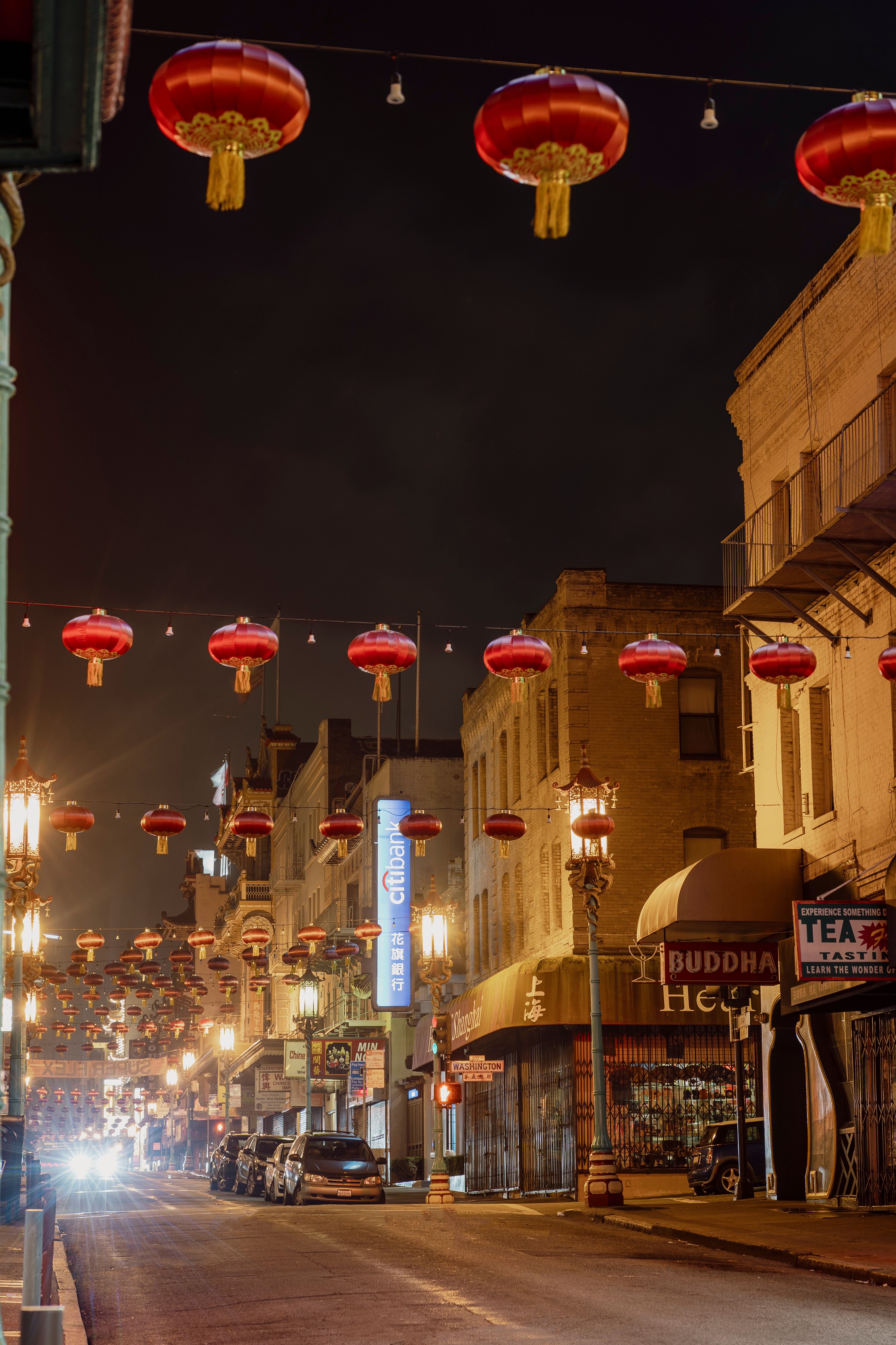 Vibrant street scene in Chinatown at night featuring red Chinese lanterns hanging overhead.