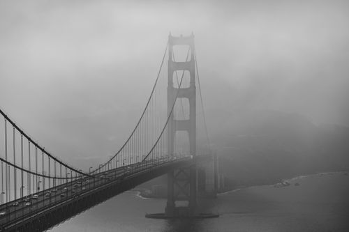 Free A moody black and white photo capturing the foggy Golden Gate Bridge from a distance. Stock Photo