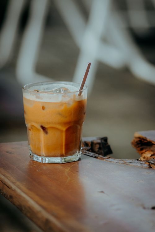 Free Close-up of a refreshing iced coffee with a straw on a rustic wooden table. Stock Photo