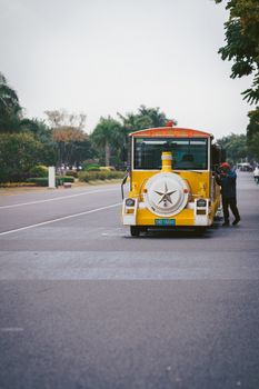 A charming yellow tourist train with a star emblem travels down a scenic, tree-lined road.