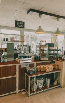 Warm café interior in Indonesia featuring a counter with pastries and packaged goods under warm lighting.