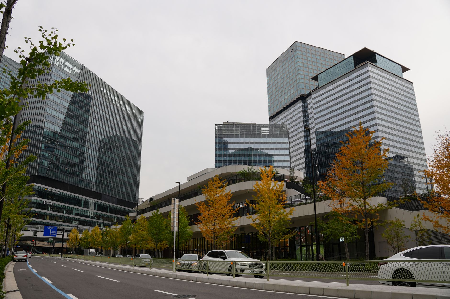 Modern skyscrapers surrounded by autumn foliage in Osaka, Japan, capturing a blend of nature and urban architecture.
