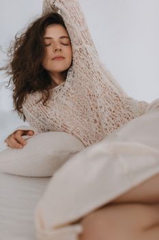 Relaxed woman in a cozy knit sweater enjoys a peaceful moment indoors.