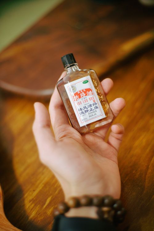Free Close-up of a hand holding a traditional medicinal oil bottle with Chinese text label. Stock Photo