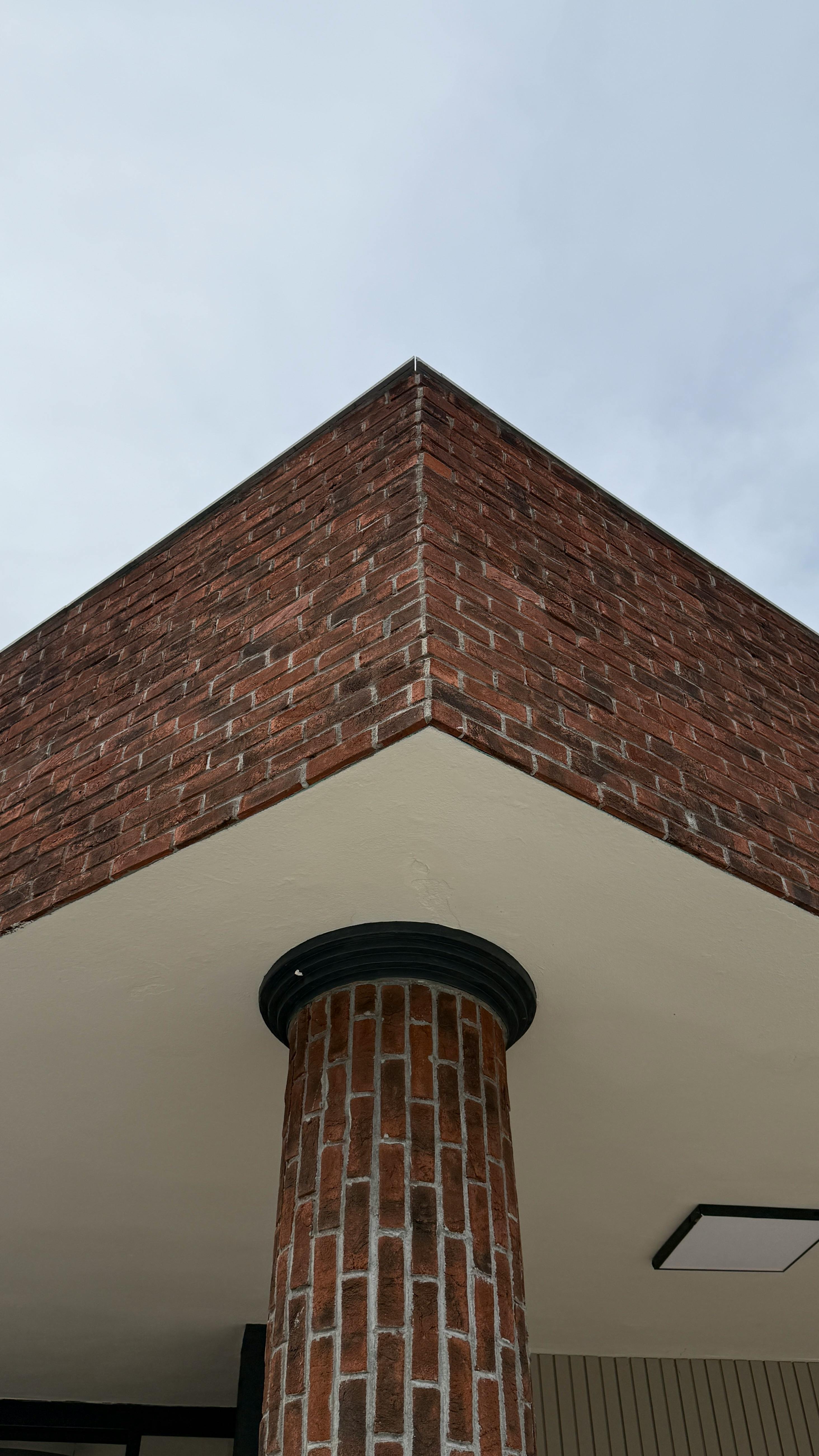Gratis Vista en ángulo bajo de un edificio de esquina de ladrillo rojo con una columna cilíndrica. Foto de stock