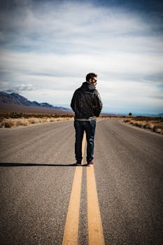 一个孤独的男人站在荒无人烟的高速公路上，拥抱冒险