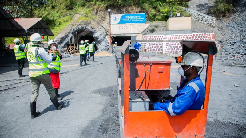 Workers at an outdoor mining site with a focus on rail transport safety.