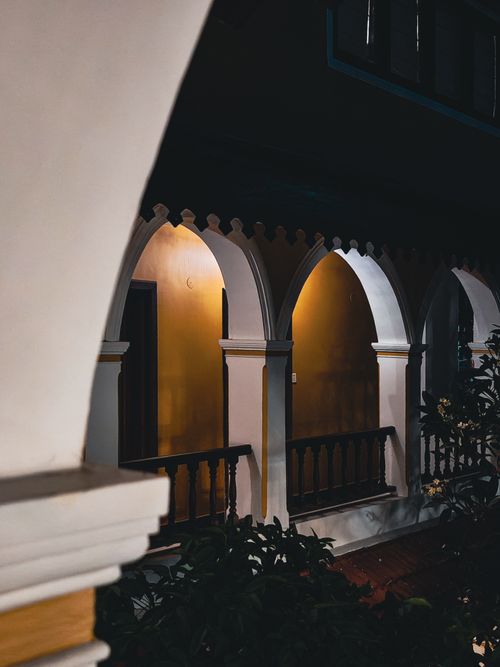 Free A beautifully lit hallway with elegant arches casting shadows during nighttime. Stock Photo