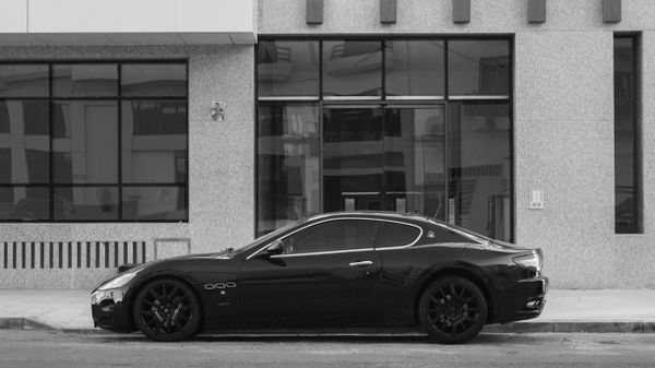 Dark sedan parked in front of a modern building — photo by Hassan Bouamoud on Pexels