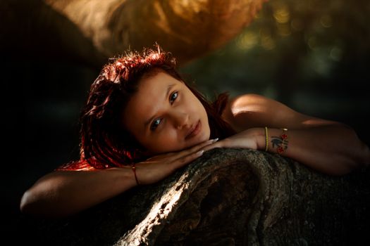 A woman peacefully resting on a tree trunk, surrounded by nature.