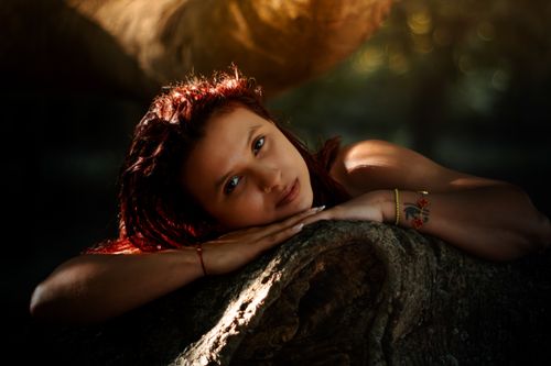 Free A woman peacefully resting on a tree trunk, surrounded by nature. Stock Photo