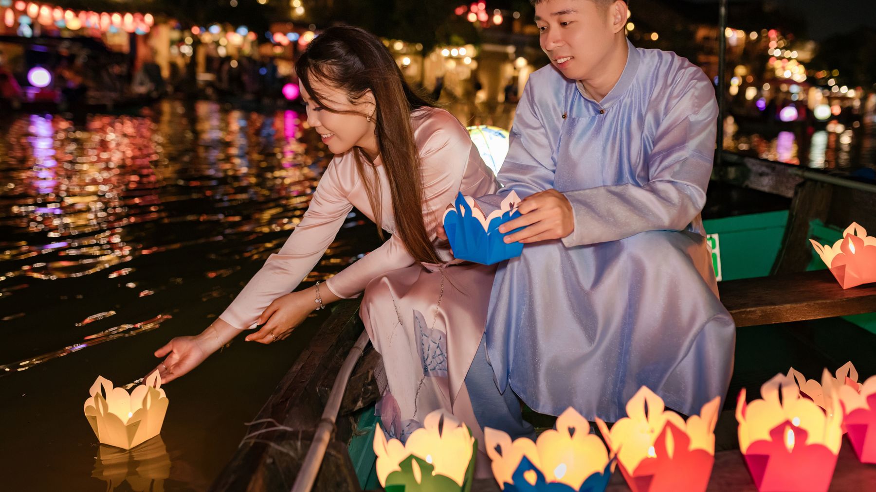 Couple enjoying lantern festival on Hoi An river at night.