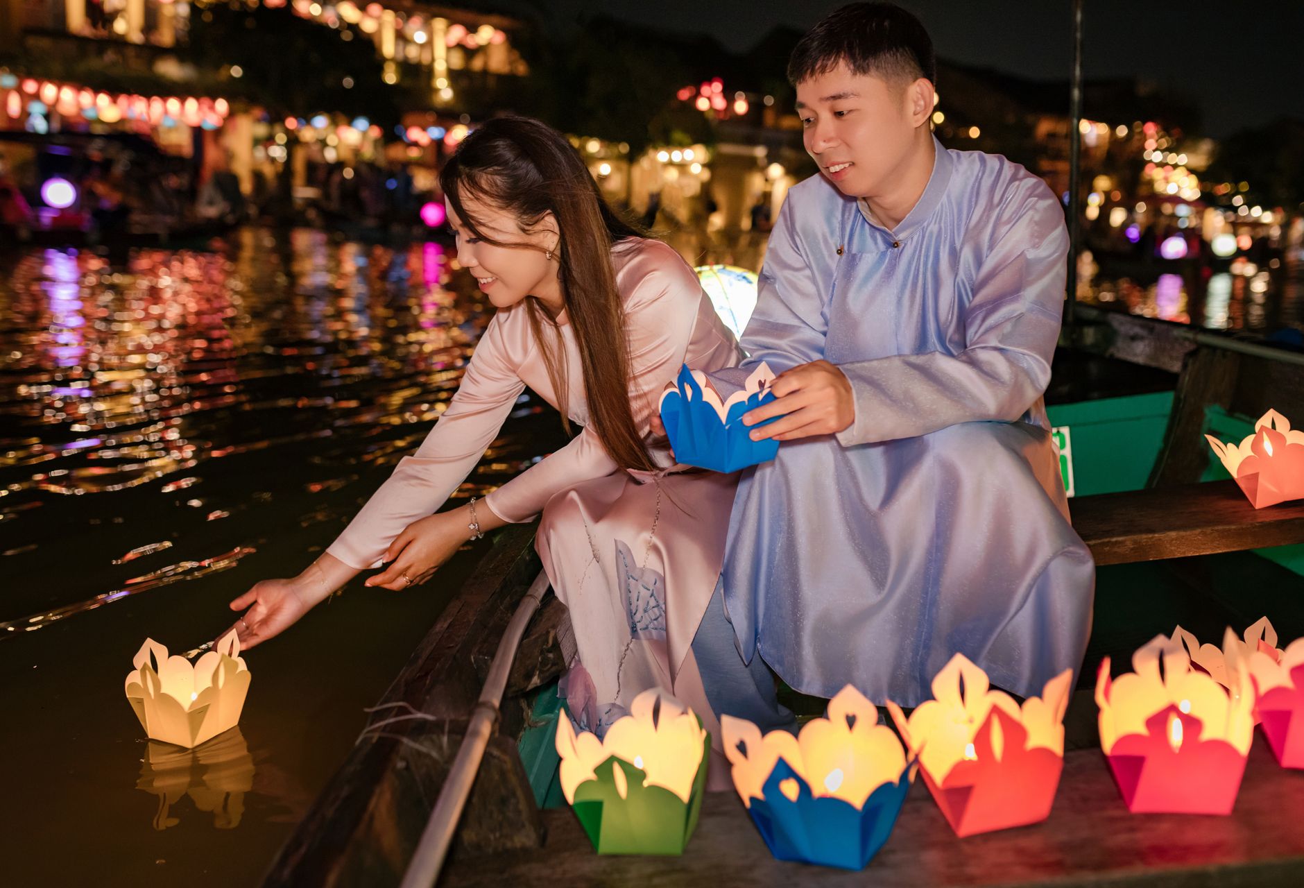 Pareja disfrutando del festival de los faroles en el río de Hoi An por la noche.