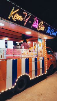 Vibrant ice cream truck with neon lights at night serving desserts.