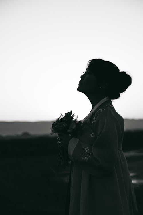 Vrouw Die In Grijze Jurk Met Lange Mouwen Een Boeket Bloemen Houdt