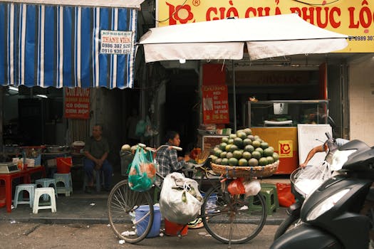 Busy street market scene with a vendor's bicycle loaded with goods in Vietnam.