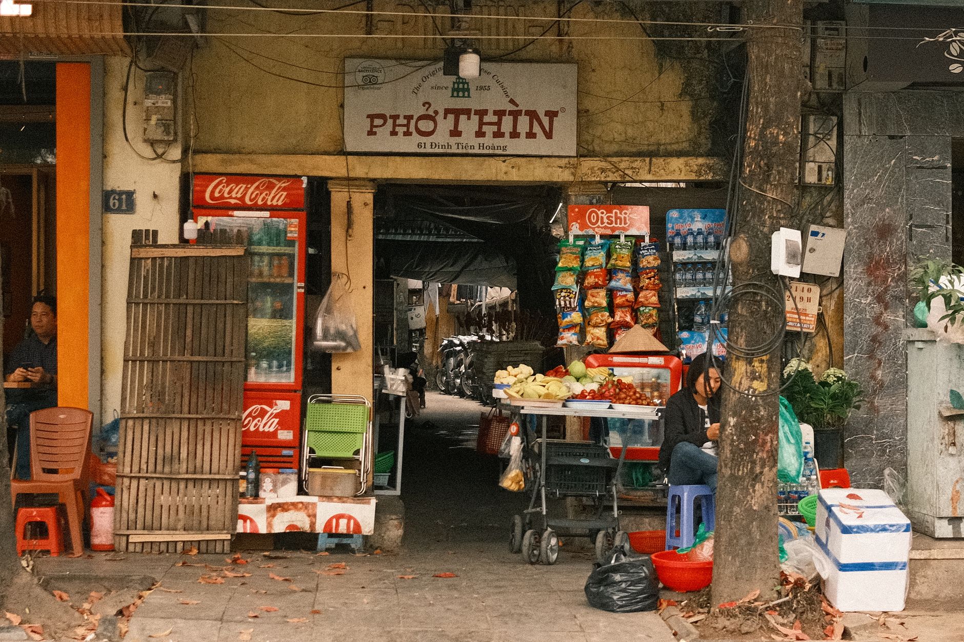 Street market scene in Hanoi with food stall, fresh produce, and local snacks.