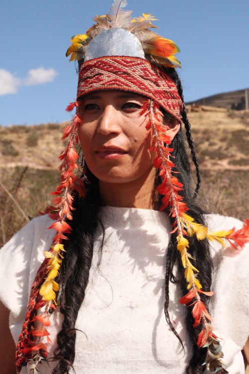 Free A person wearing traditional attire with feather adornments, outdoors under a sunny sky. Stock Photo