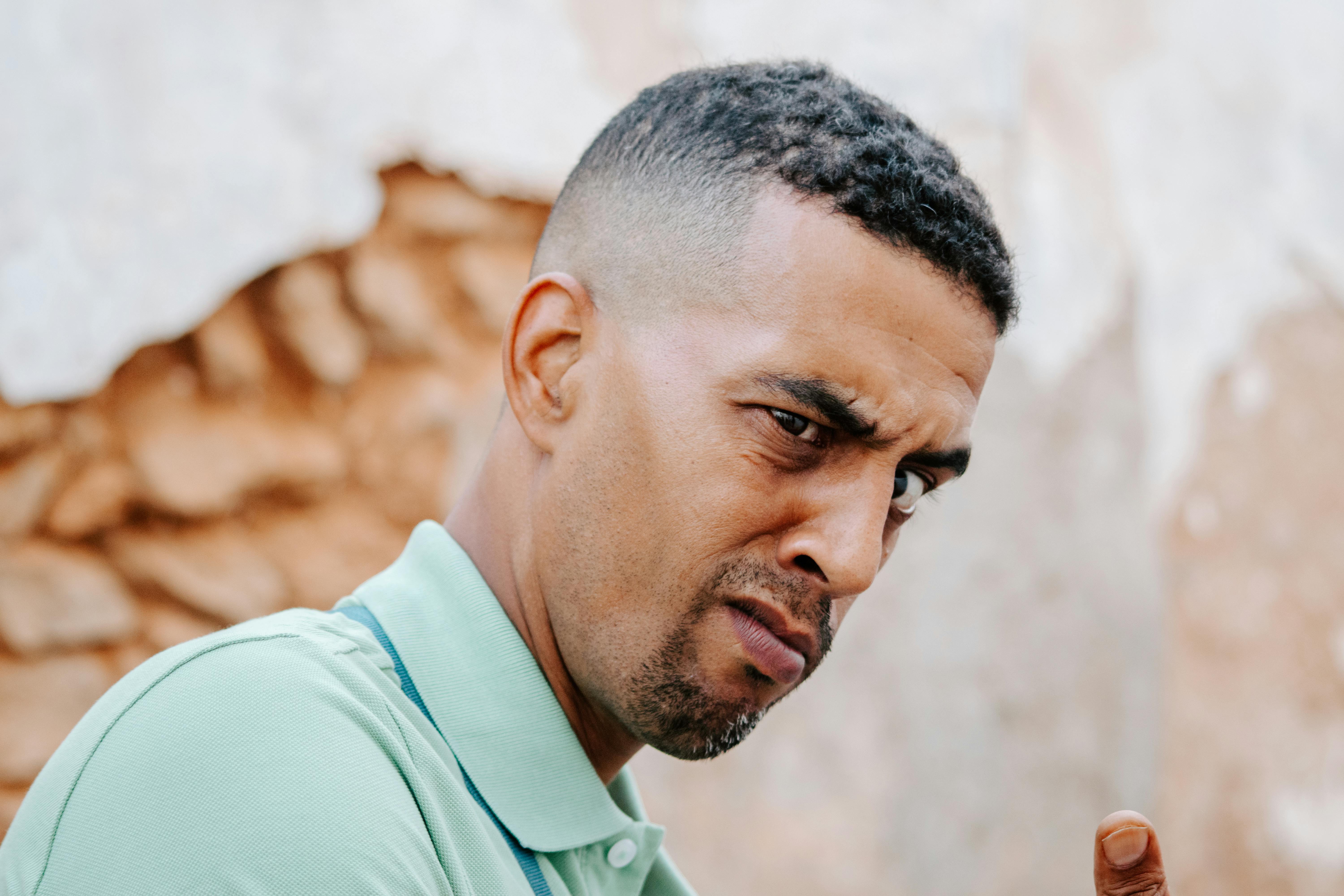 Close-up portrait capturing a man's contemplative expression against a textured wall in Rabat, Morocco.
