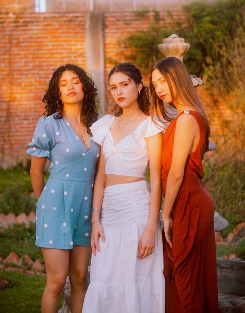 Free Three stylish women posing in the golden hour light, showcasing fashion and elegance outdoors. Stock Photo