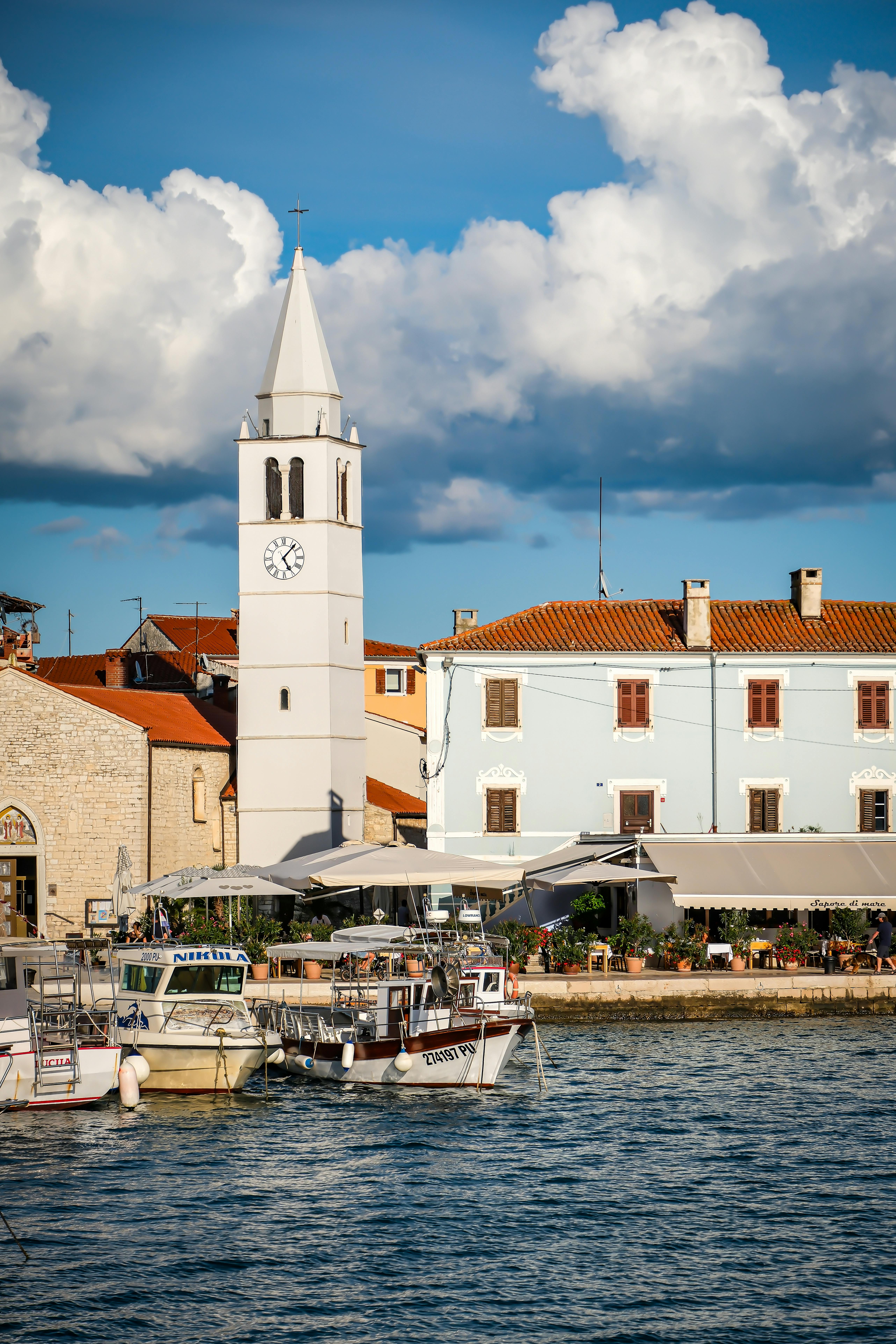 Scenic view of Fažana's waterfront showcasing historic church tower and vibrant seaside. Perfect travel destination.