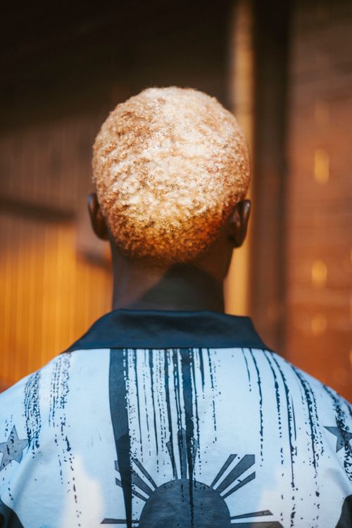 Free Stylish person with bleached blonde hair facing away, wearing a patterned jacket. Stock Photo