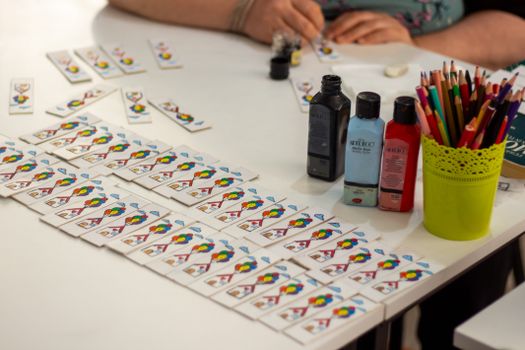 Close-up of crafting setup with playing cards, paints, and pencils on a table.