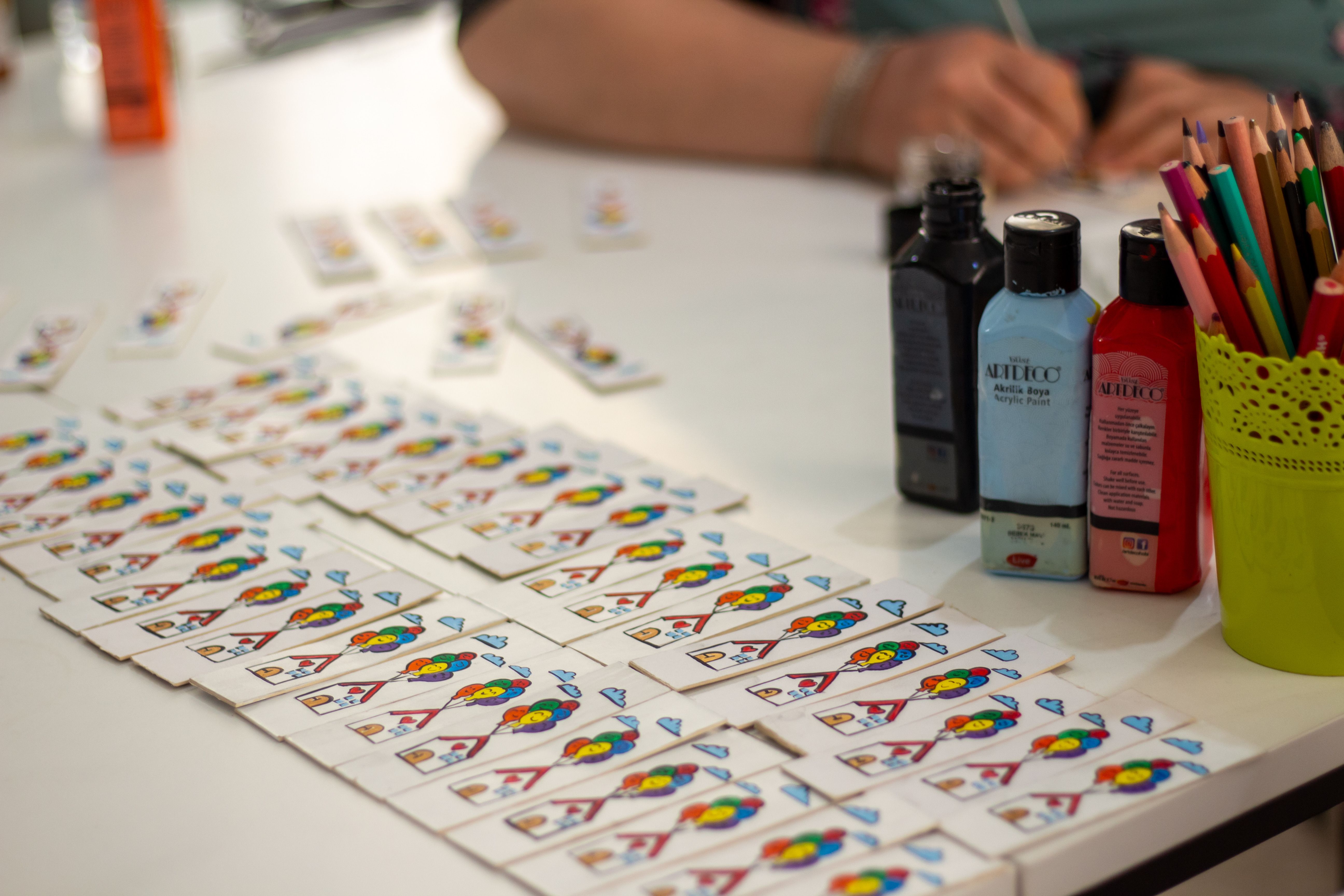 Gratuit Espace de travail créatif comprenant des peintures, des cartes à jouer et des crayons de couleur, idéal pour les activités artistiques et manuelles. Photos
