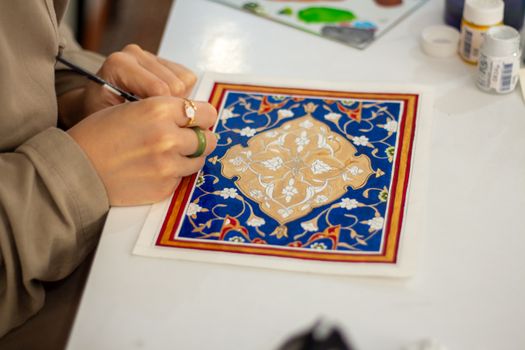 Close-up of an artist working on a traditional geometric design with intricate patterns.