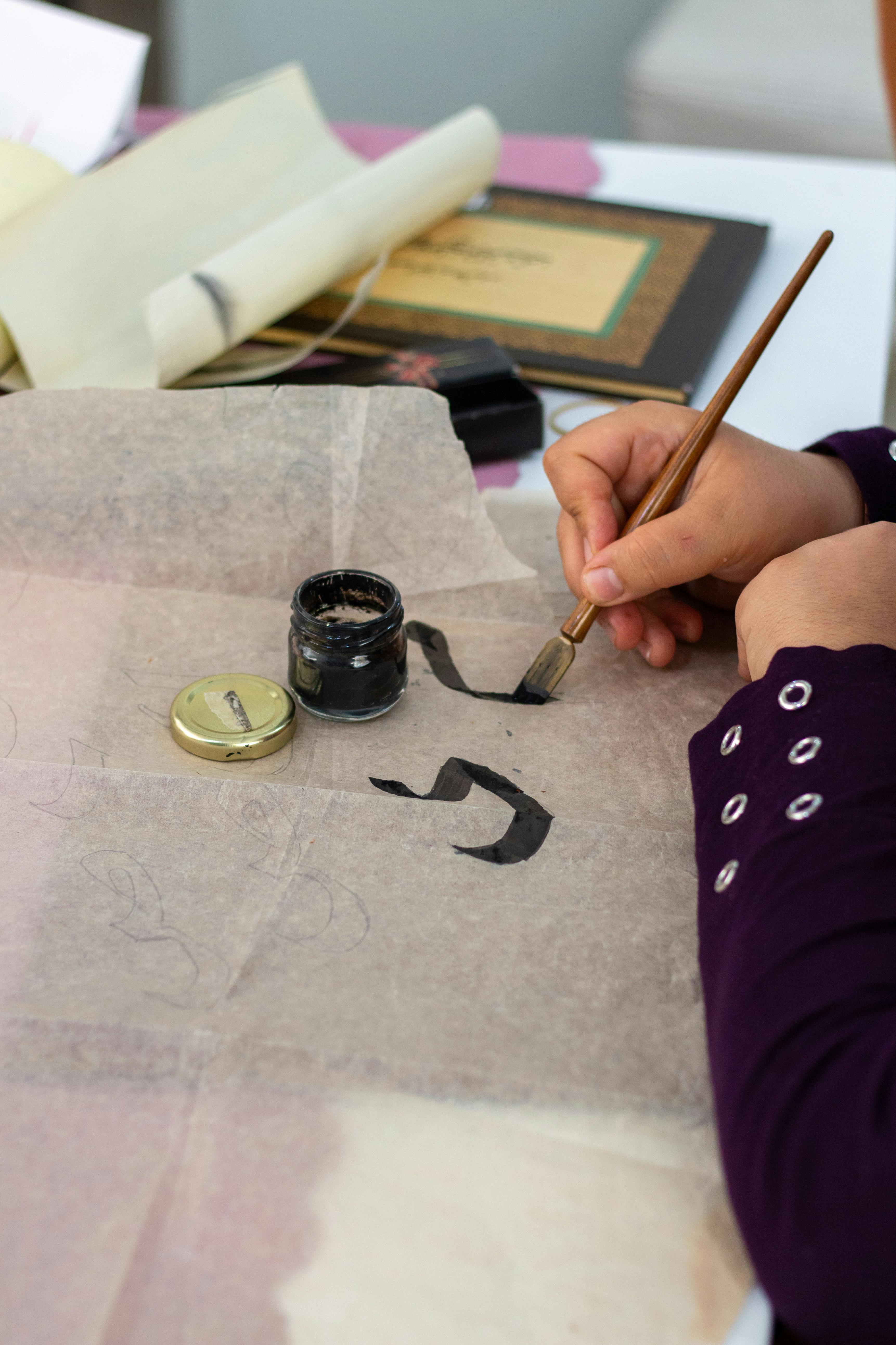 Gratis Esercizio manuale di calligrafia araba con inchiostro e pennello su carta pergamena. Foto a disposizione