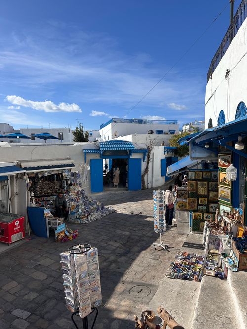 Free A vibrant Tunisian street market featuring shops with iconic blue doors and a variety of cultural artifacts. Stock Photo